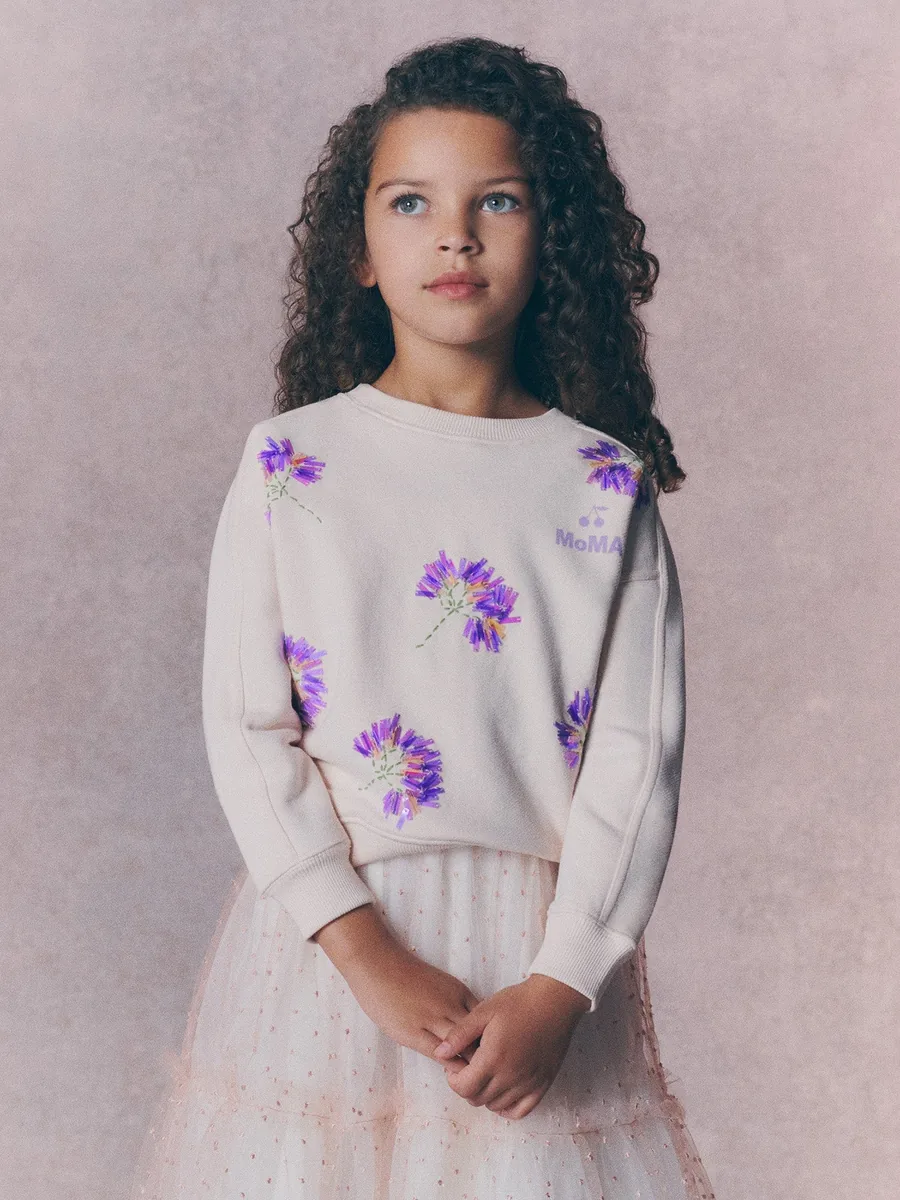 Girl in the Bonpoint x MoMA sweatshirt with flowers and beads